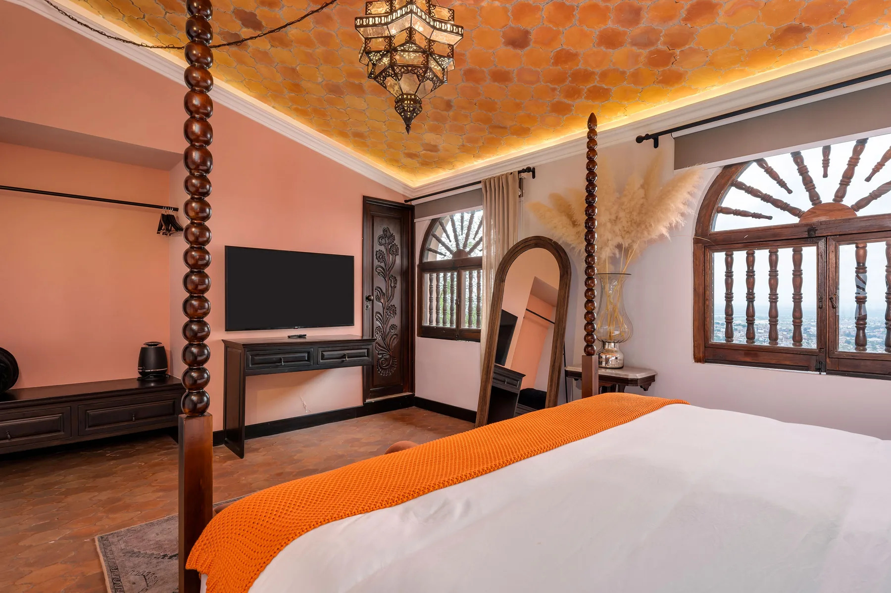 A bedroom with a bed, television, and arched windows.