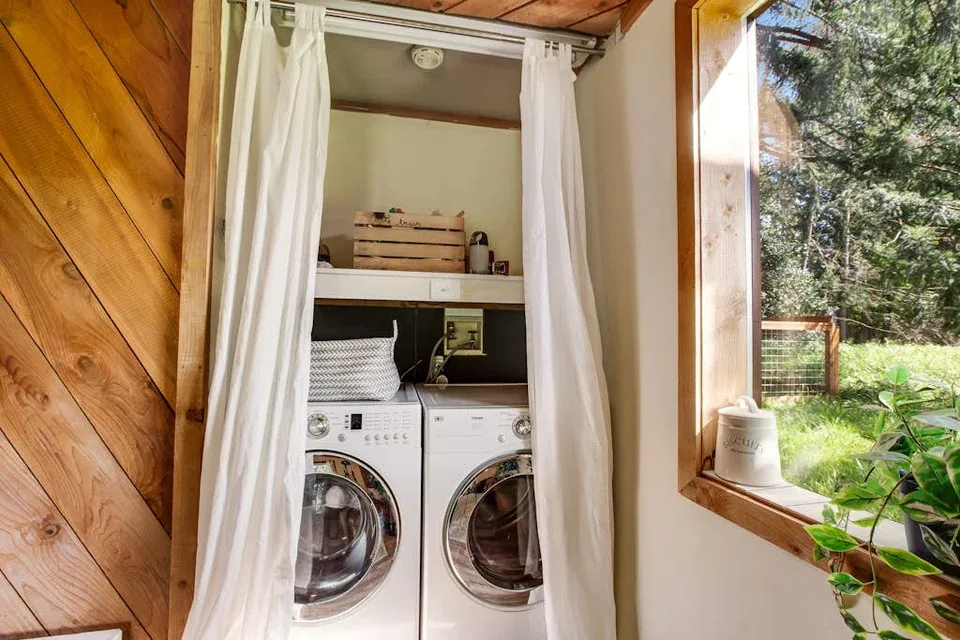 A laundry area with two front-loading machines behind white curtains.