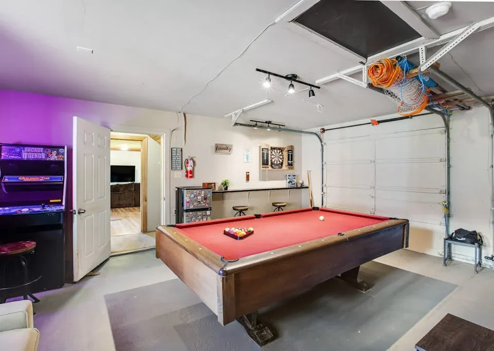A game room with a red-felt pool table and arcade machine.