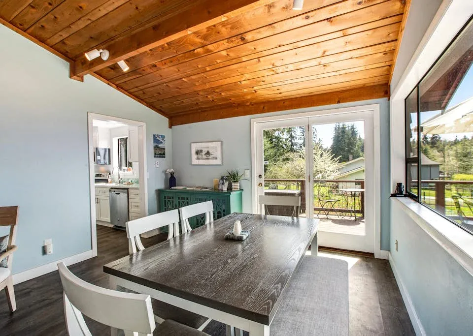 A dining area with a long table beside glass doors opening onto a balcony.
