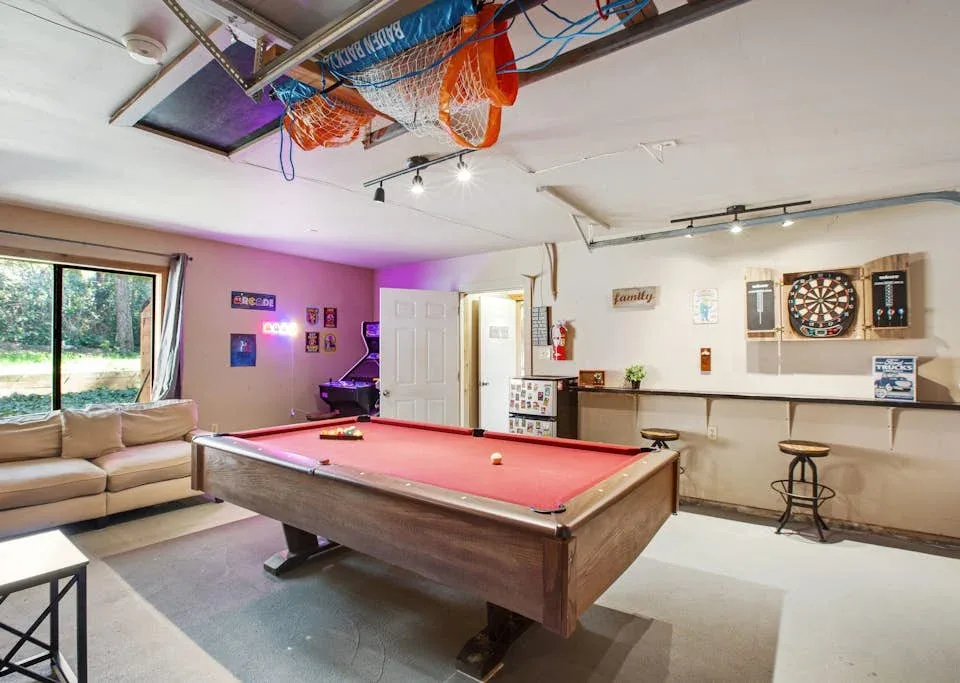 A recreation room with a pool table, seating, and dartboards.