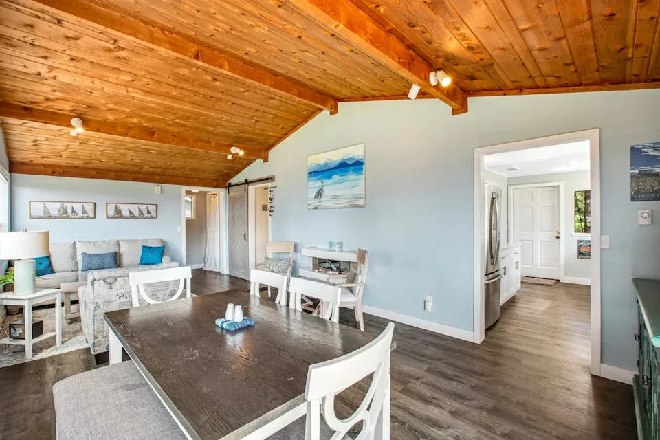 A dining and living area with a wooden ceiling and an open doorway.