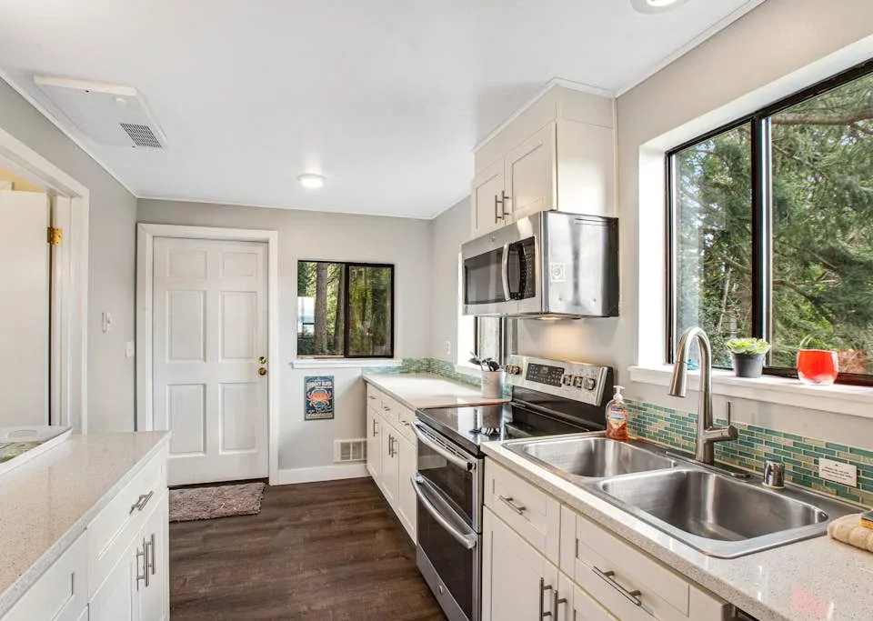 A bright kitchen with white cabinets, stainless steel appliances, and a double sink.