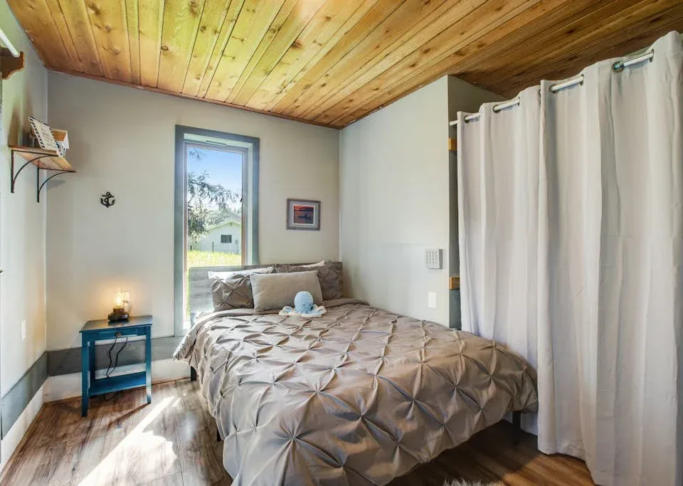 A bedroom with a bed beside a window and a curtained area.