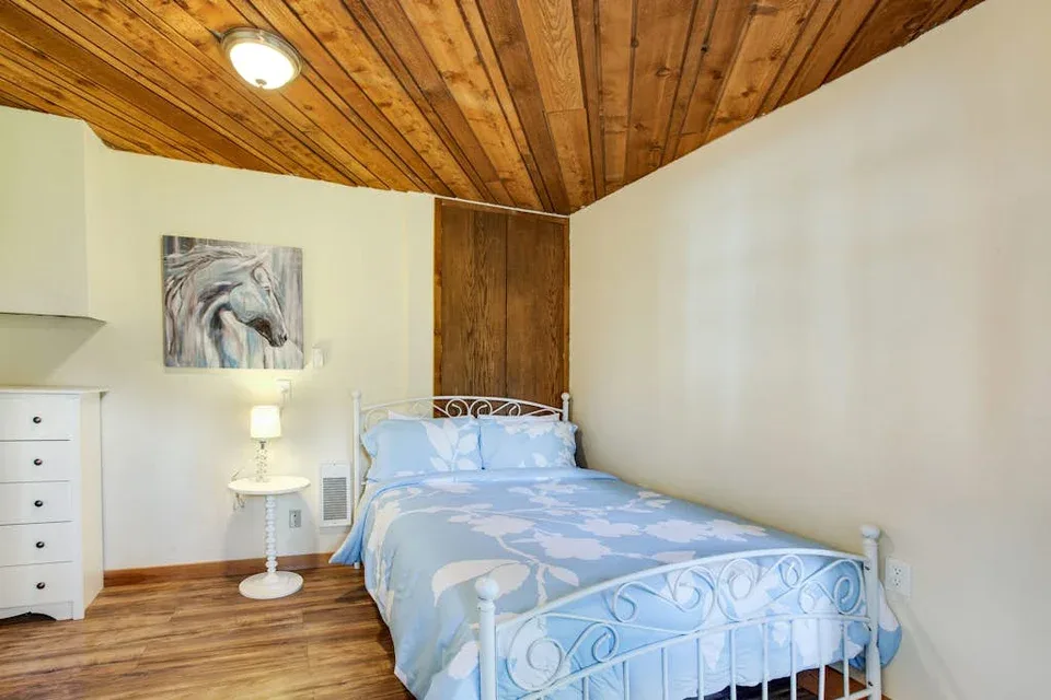 A bedroom with a blue bed beneath a wood-paneled ceiling.