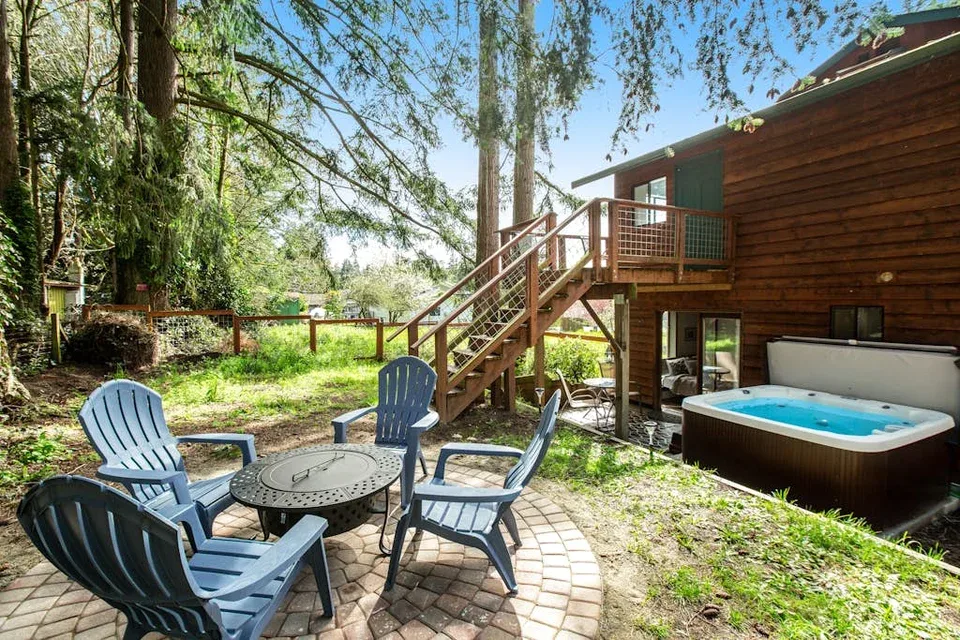 An outdoor patio with seating and a hot tub beside a wooden cabin.