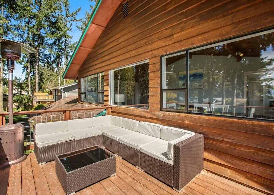 A wooden deck with an outdoor seating area beside a house.