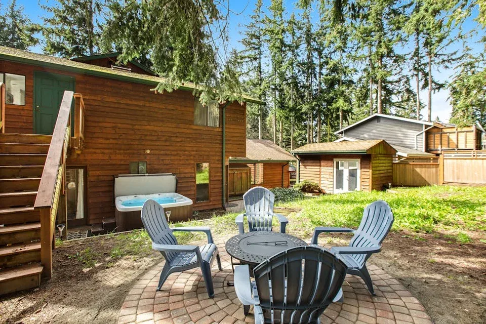 Outdoor seating area with several chairs around a table beside wooden cabins.