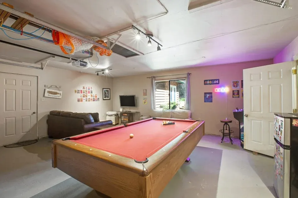 A recreation room with a pool table, seating, and colorful wall lights.