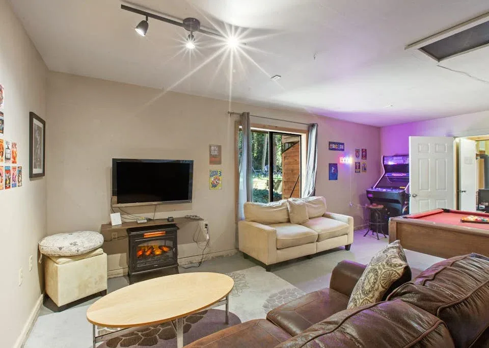 A living room with a television, seating, and a pool table.