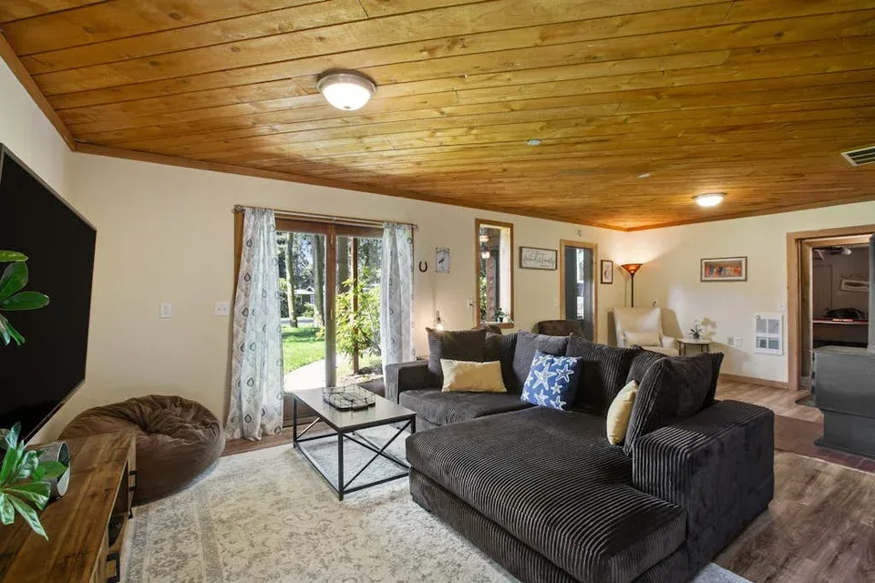 A living room with sectional seating, a coffee table, and glass doors opening to a garden.
