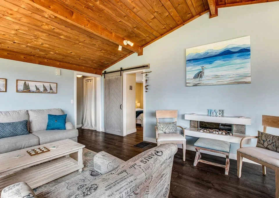 A living room with seating, a coffee table, and a wood-paneled ceiling.