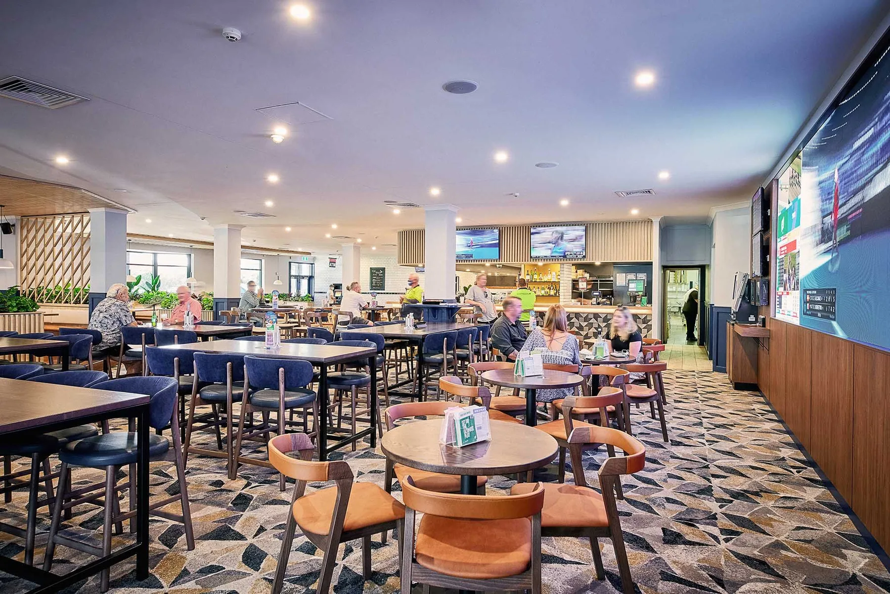 Espacio representativo del hotel: Comedor de hotel con mesas y asientos bajo una iluminación brillante.
