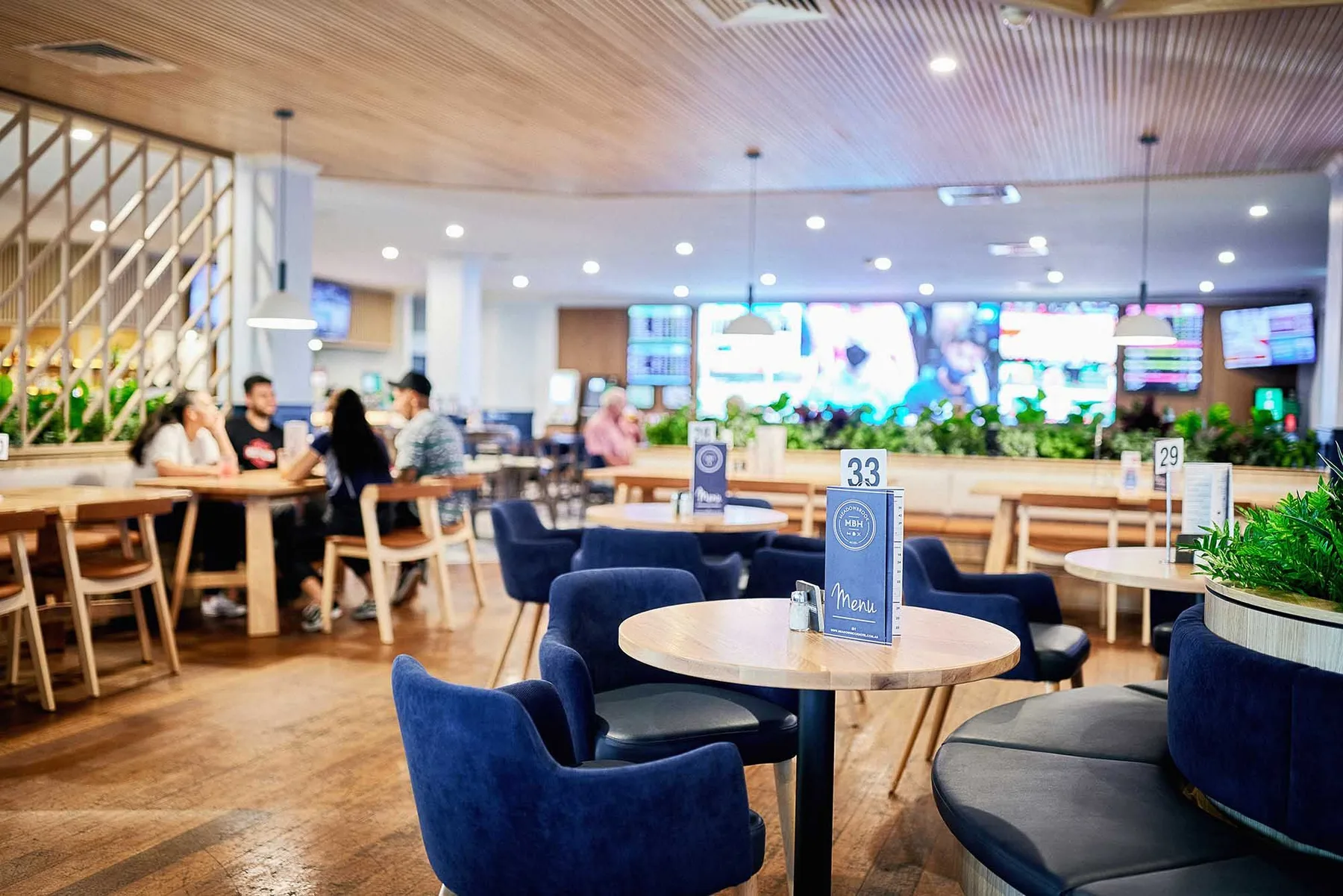 Espacio representativo del hotel: Un comedor de restaurante con mesas y asientos tapizados azules.
