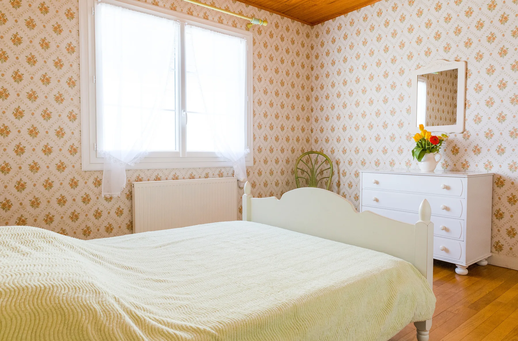 A bedroom with a bed, a window, and a white dresser.