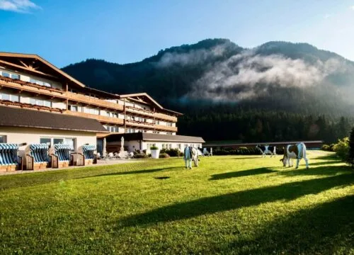 Representative hotel space: A hotel building overlooks a grassy lawn with mountains rising behind it.