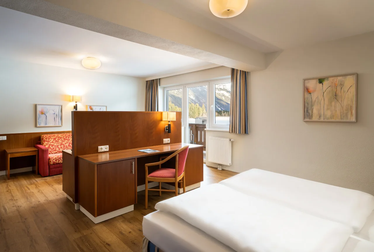 Representative hotel space: A hotel bedroom with a bed, desk, and window overlooking the mountains.