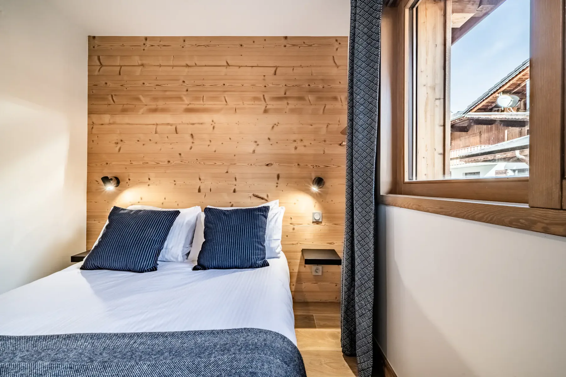 Un dormitorio con una cama bajo un cabecero de madera y una ventana.