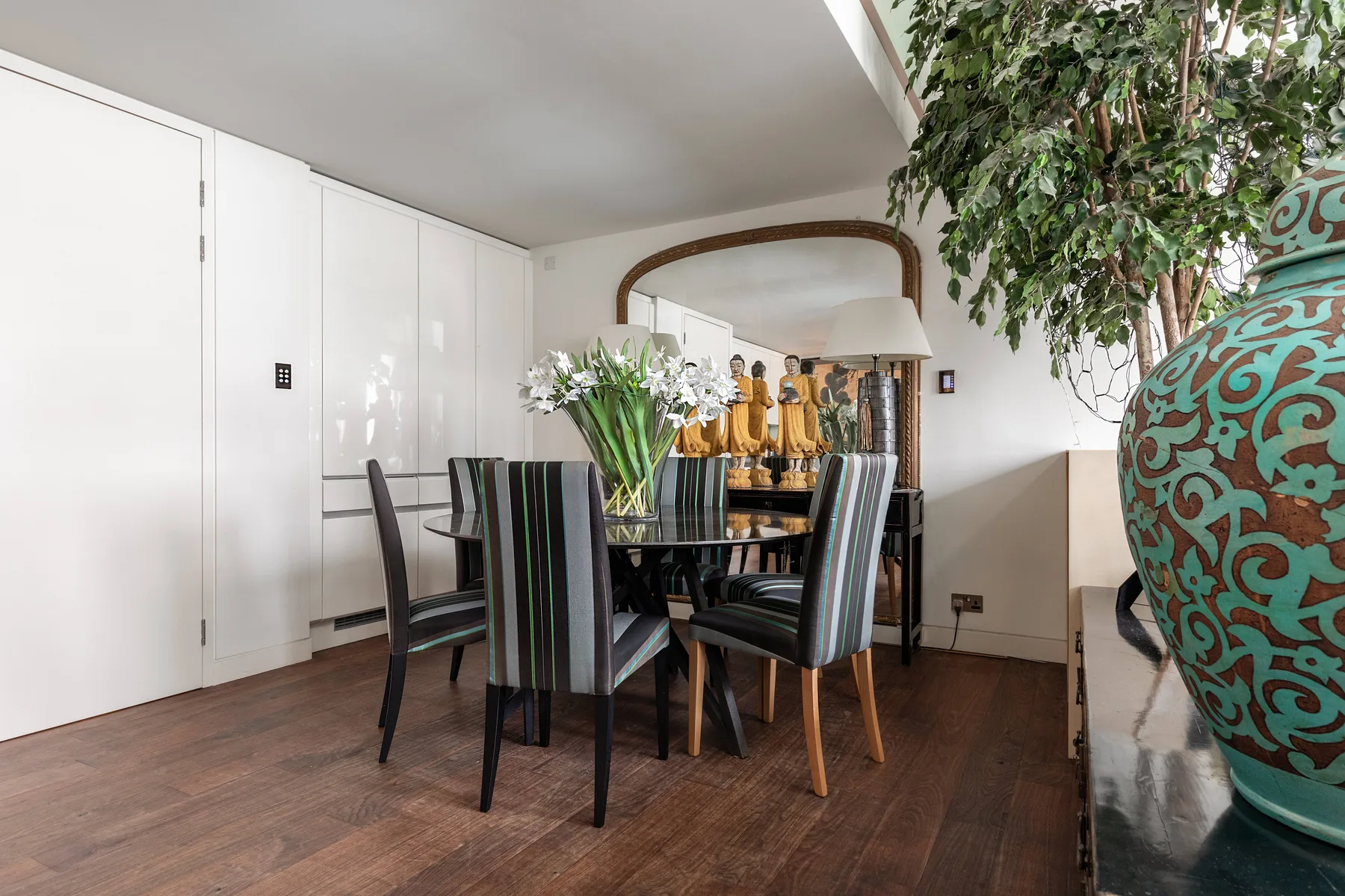 A dining area with a table, upholstered seating, and flowers.