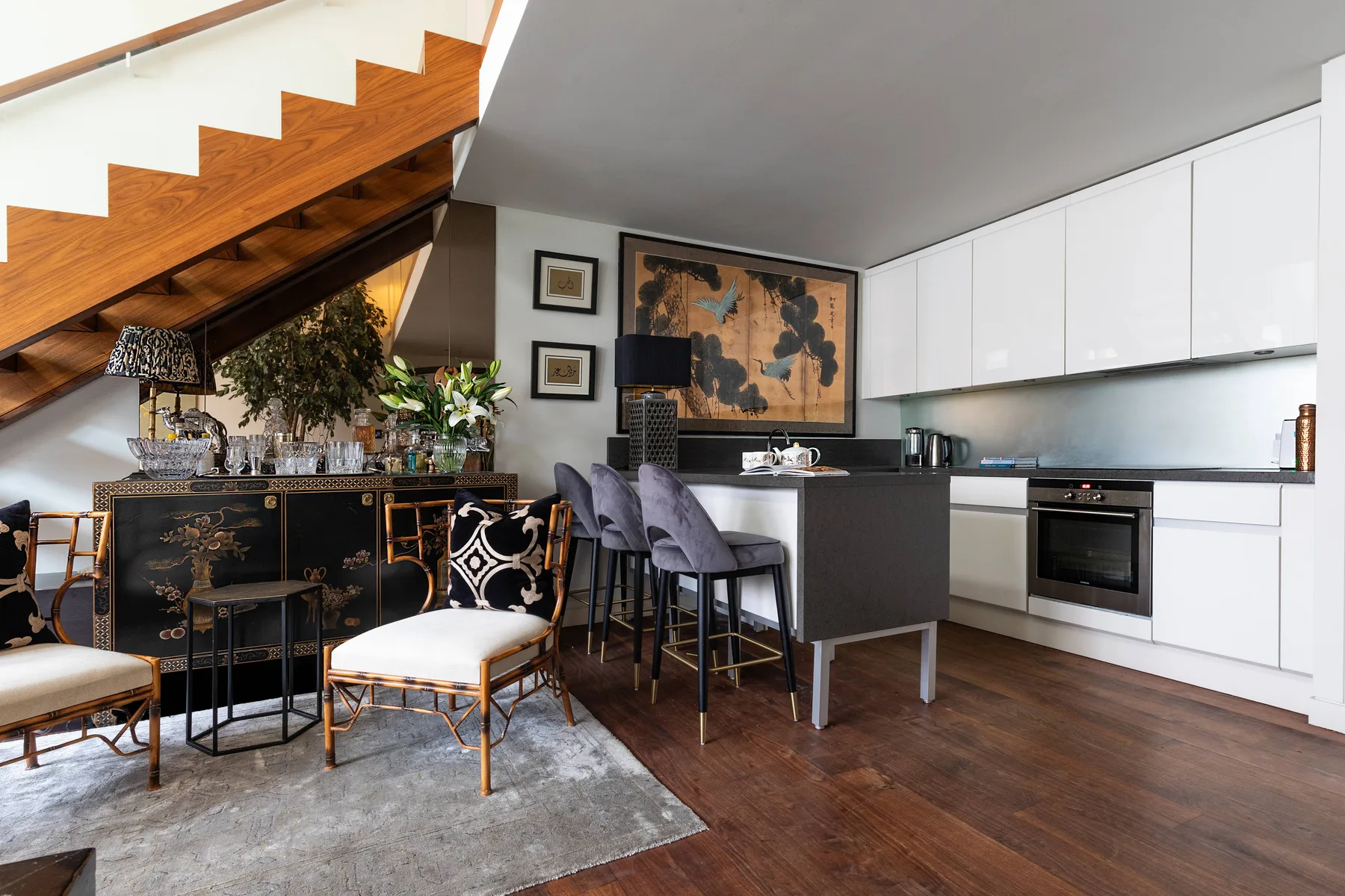 An open-plan kitchen and dining area with white cabinetry and a wooden staircase.