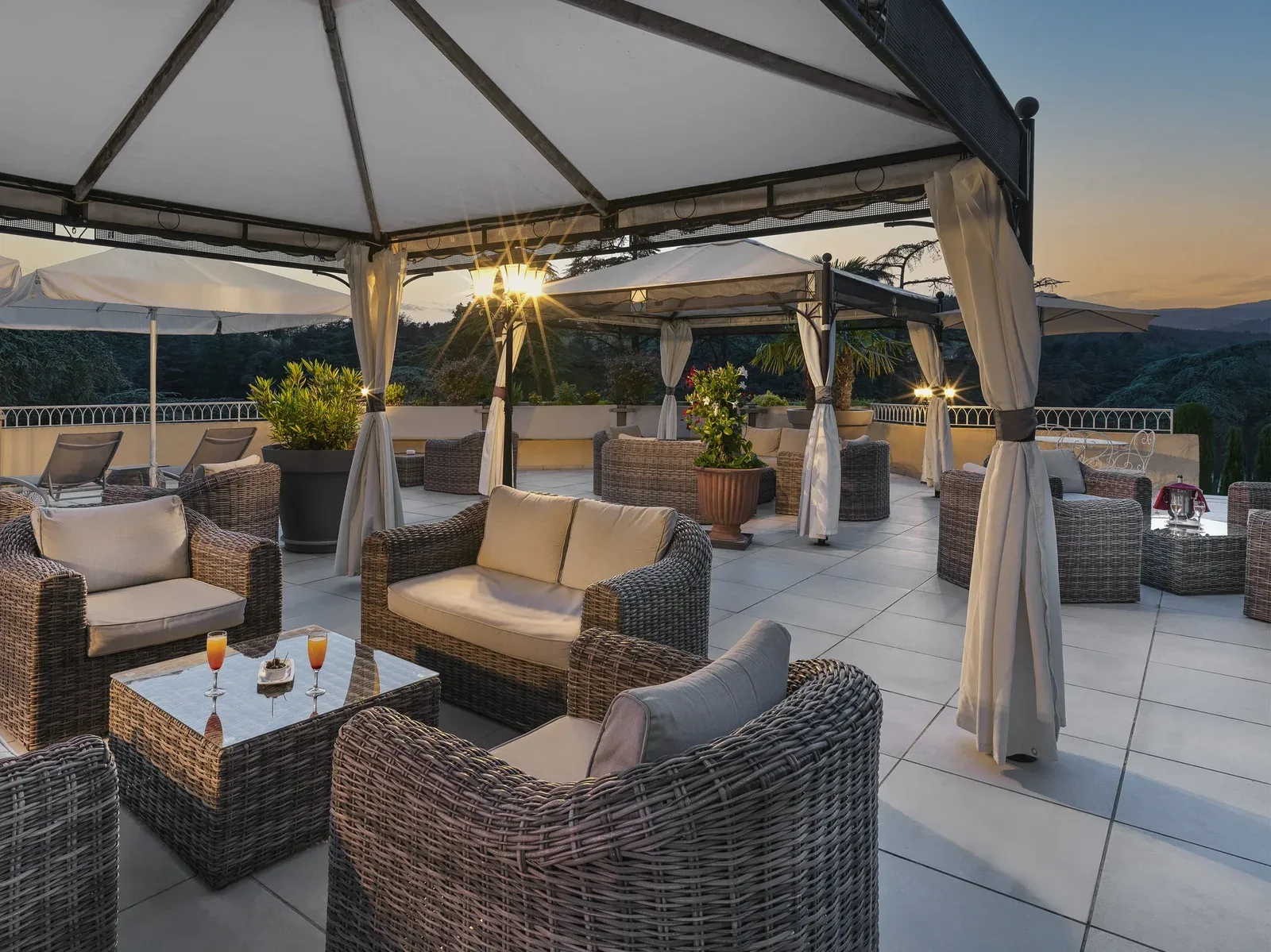 Espacio representativo del hotel: Una terraza en la azotea tiene asientos de mimbre bajo toldos de tela al atardecer.