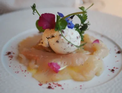 Espacio representativo del hotel: Un plato de mariscos está coronado con un huevo escalfado y flores comestibles.