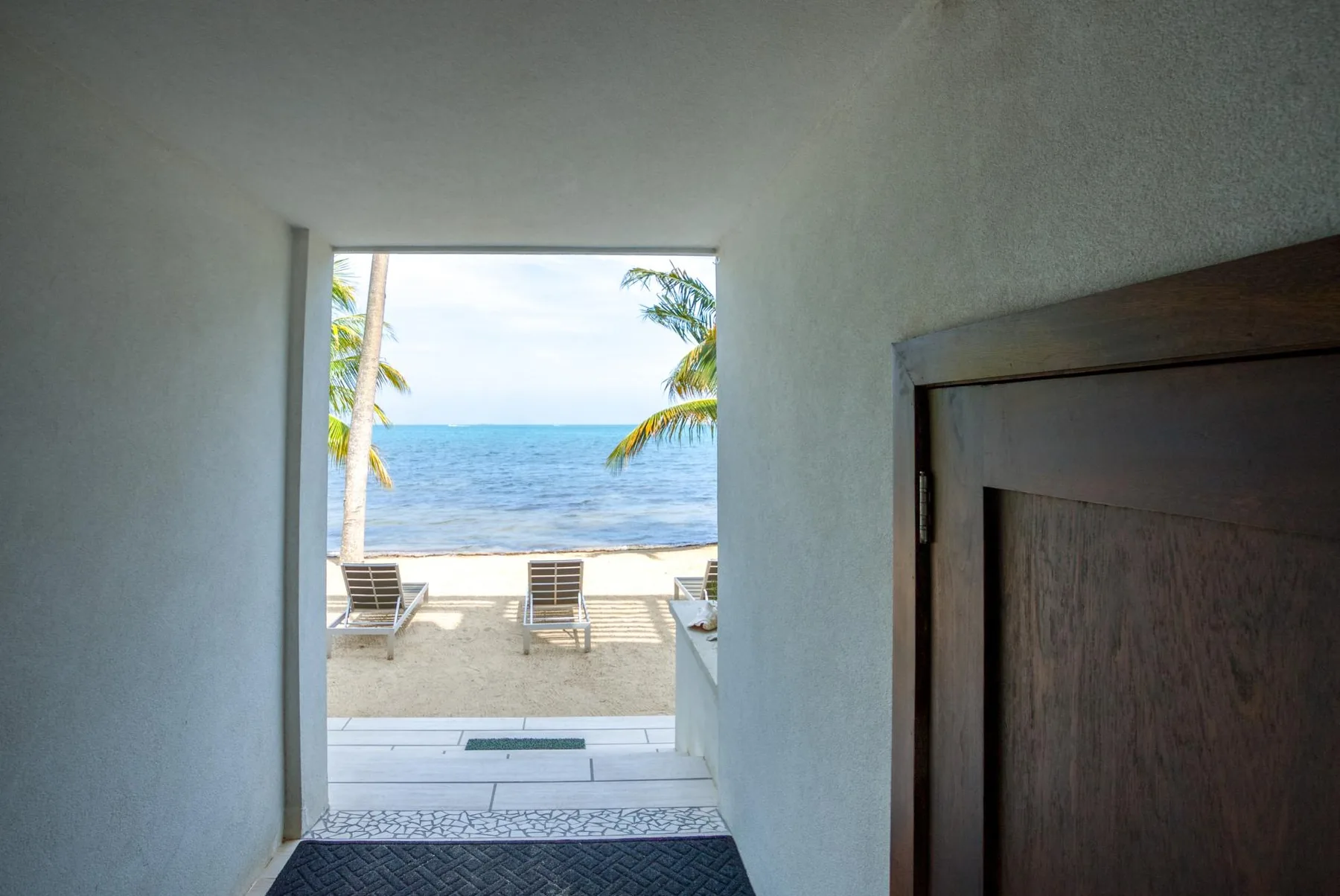 Shared amenity: A doorway opens onto a beachfront patio with seating and a view of the ocean.