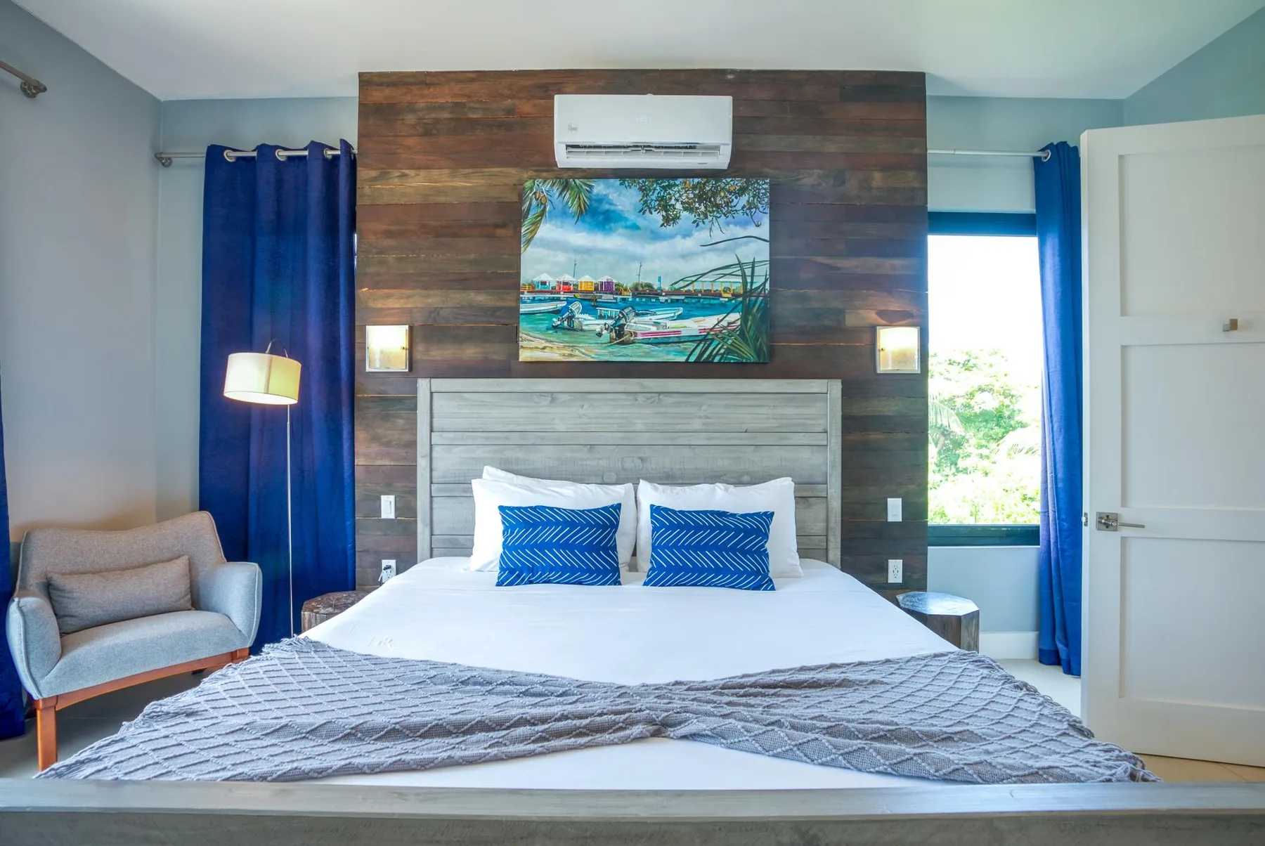 A bedroom with a bed, blue curtains, and a wooden accent wall.