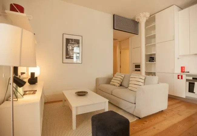 Una sala luminosa con sofá, mesa de centro y suelo de madera clara.