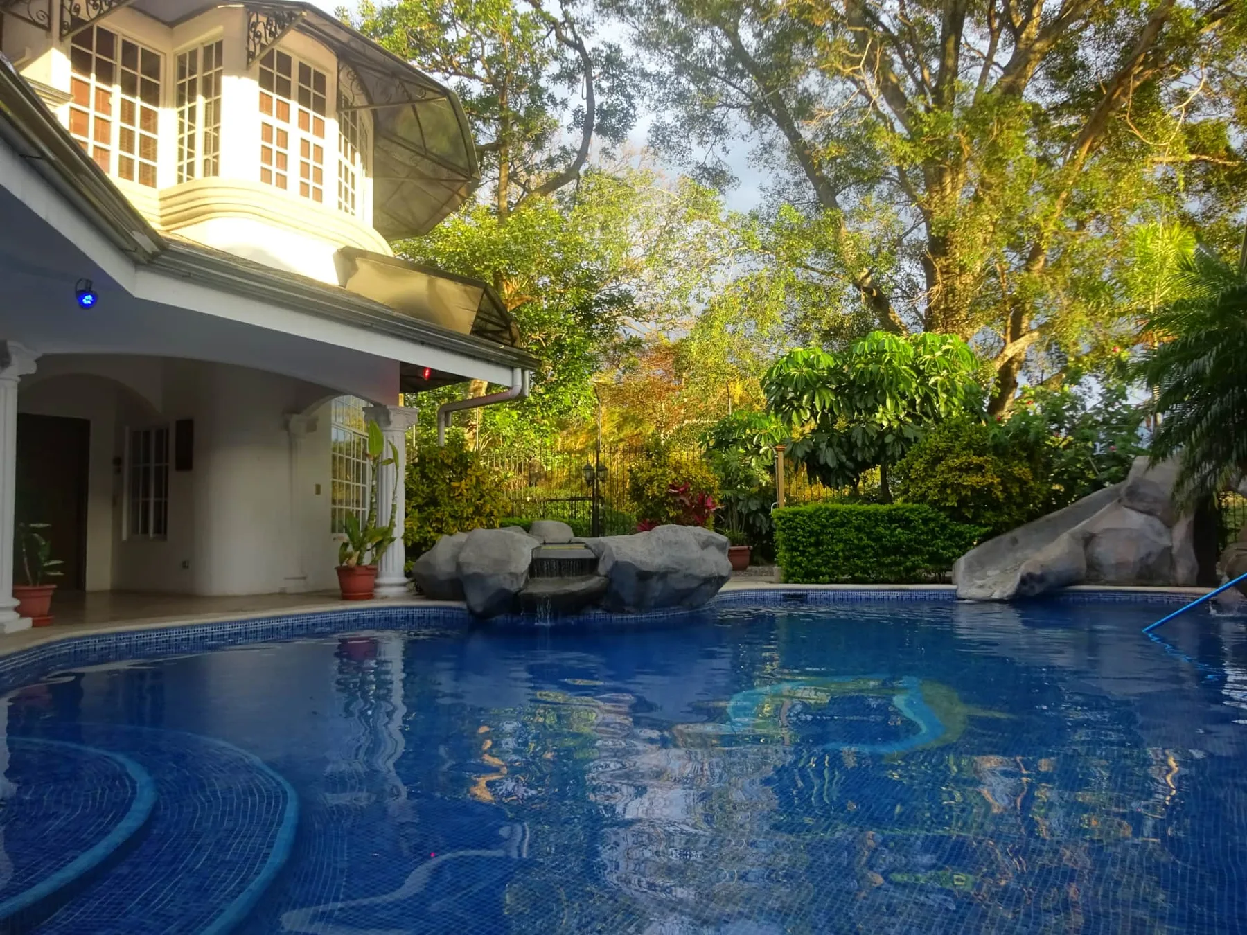 Representative hotel space: An outdoor swimming pool beside a house, surrounded by trees and greenery.