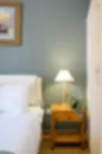 Representative hotel space: A bedroom with a bed, an armchair, and a lamp beside the wall.