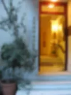 Representative hotel space: An illuminated doorway opens onto a warm interior beside a potted plant.