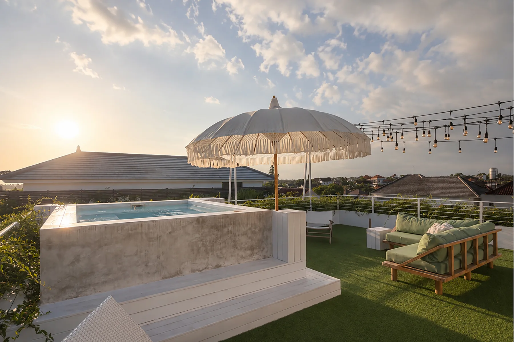 Una terraza en la azotea con piscina elevada, asientos y una sombrilla grande.