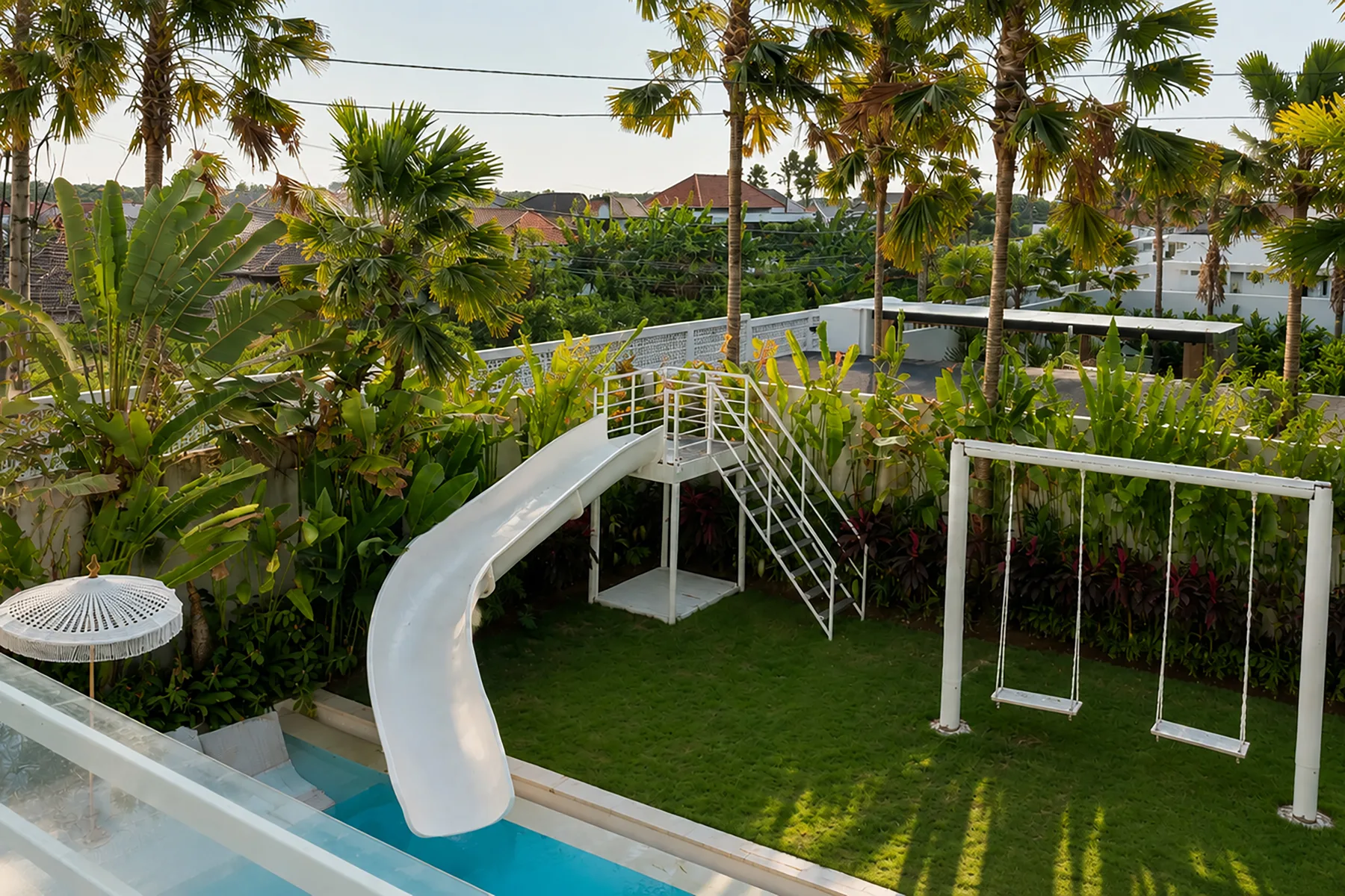 A landscaped outdoor play area features a curved slide, climbing frame, and swings.