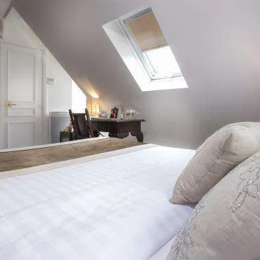 Espacio representativo del hotel: Un dormitorio con una cama bajo un techo inclinado y una claraboya.