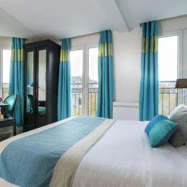 Espacio representativo del hotel: Un dormitorio con una cama tendida junto a ventanas altas.