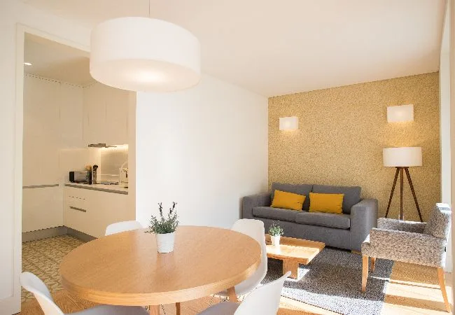 A bright living and dining area with a gray sofa and round table.