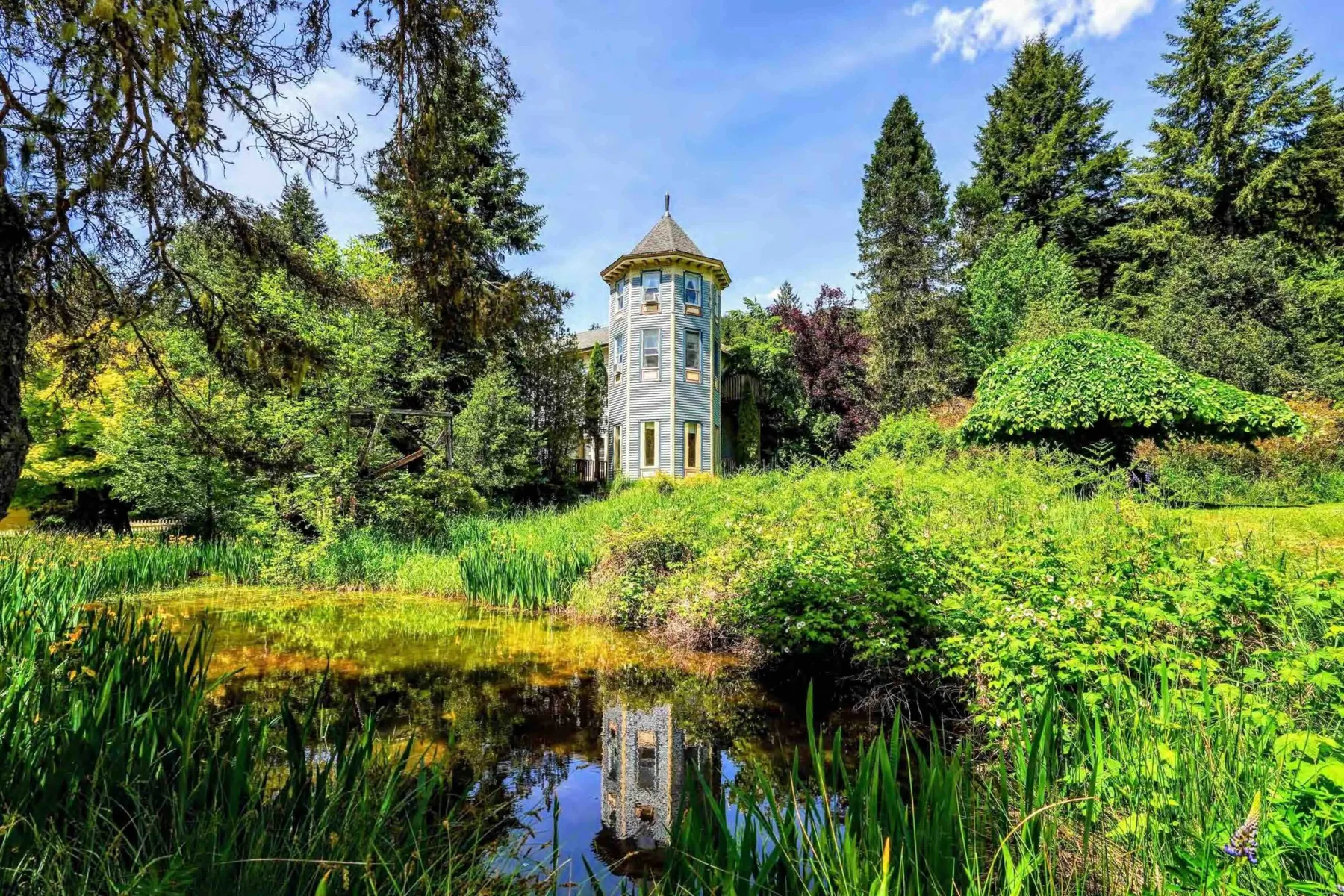 Representative hotel space: A small tower stands among lush greenery beside a reflective pond.