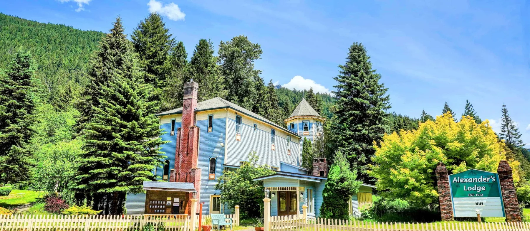 Representative hotel space: A lodge stands among tall trees beneath a blue sky.