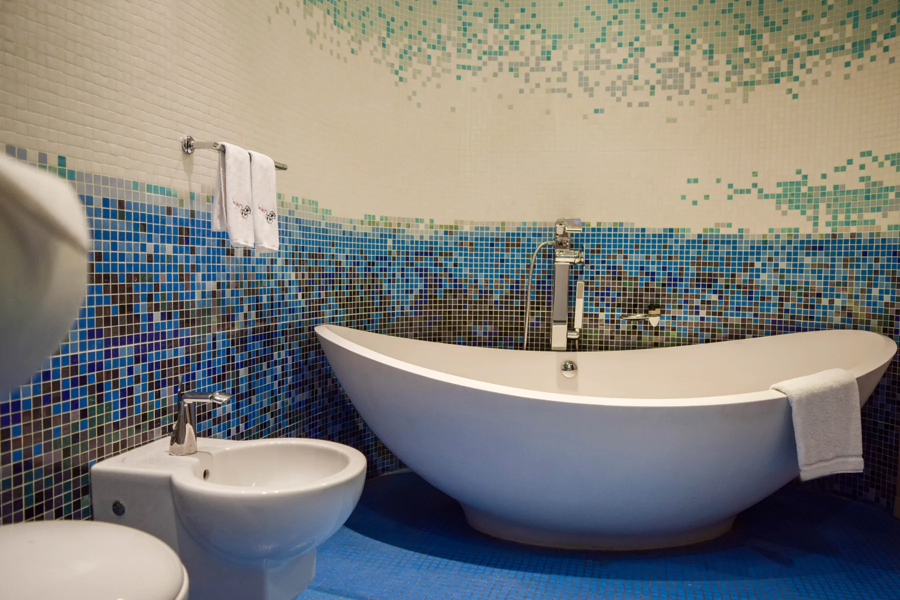 Representative hotel space: A bathroom with a freestanding bathtub and blue mosaic tiles.