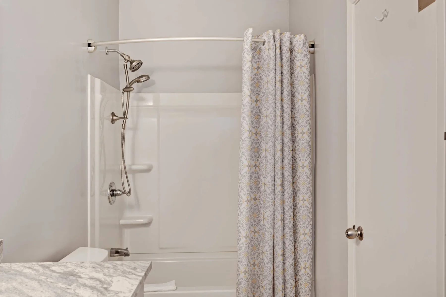Un baño con ducha y cortina estampada junto a un lavabo.