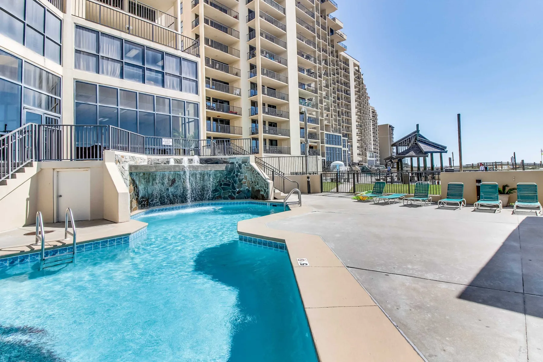Zona común: Piscina al aire libre junto a edificios altos, con tumbonas en la terraza.