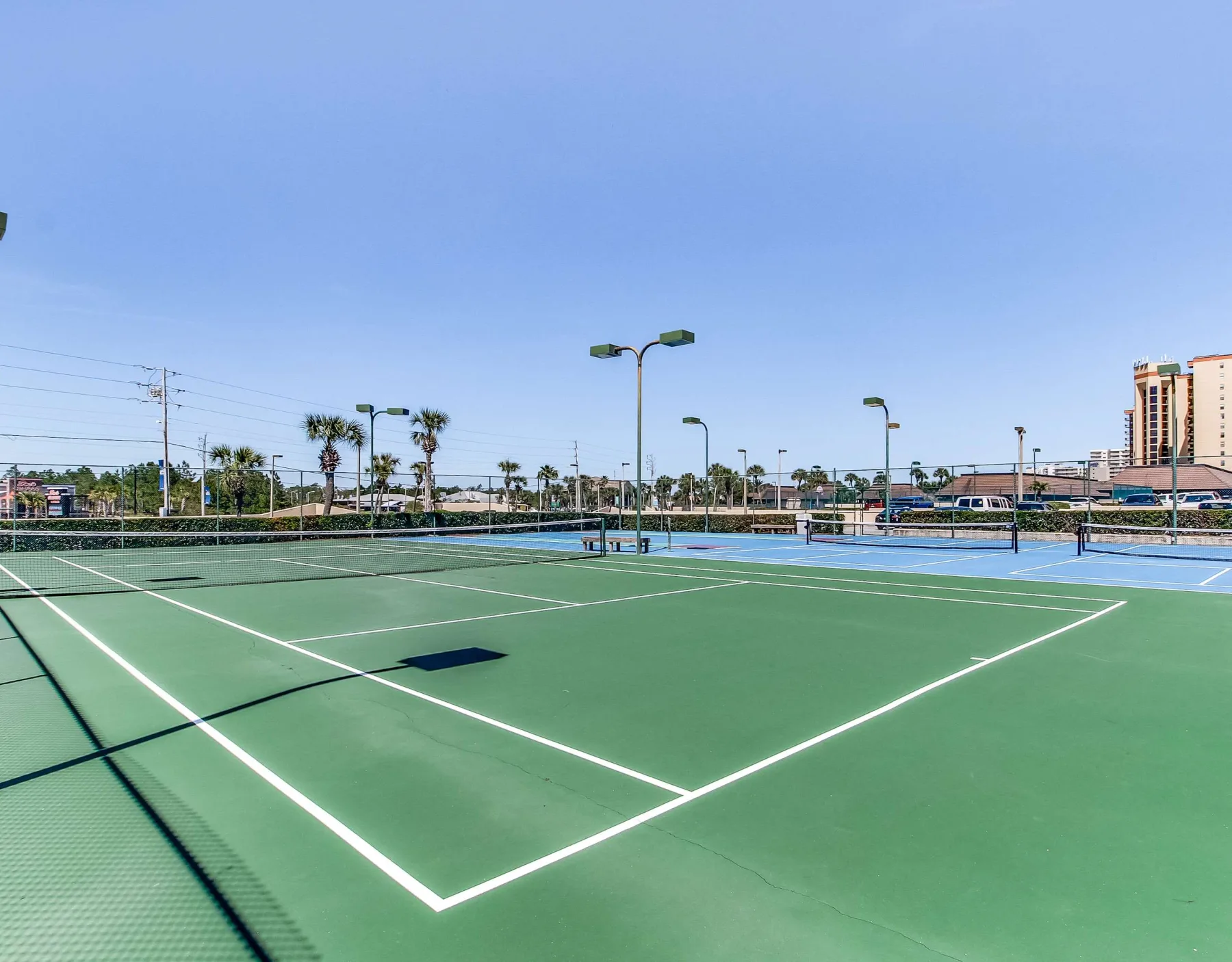 Zona común: Canchas de tenis al aire libre con superficies verdes y cercas alrededor.