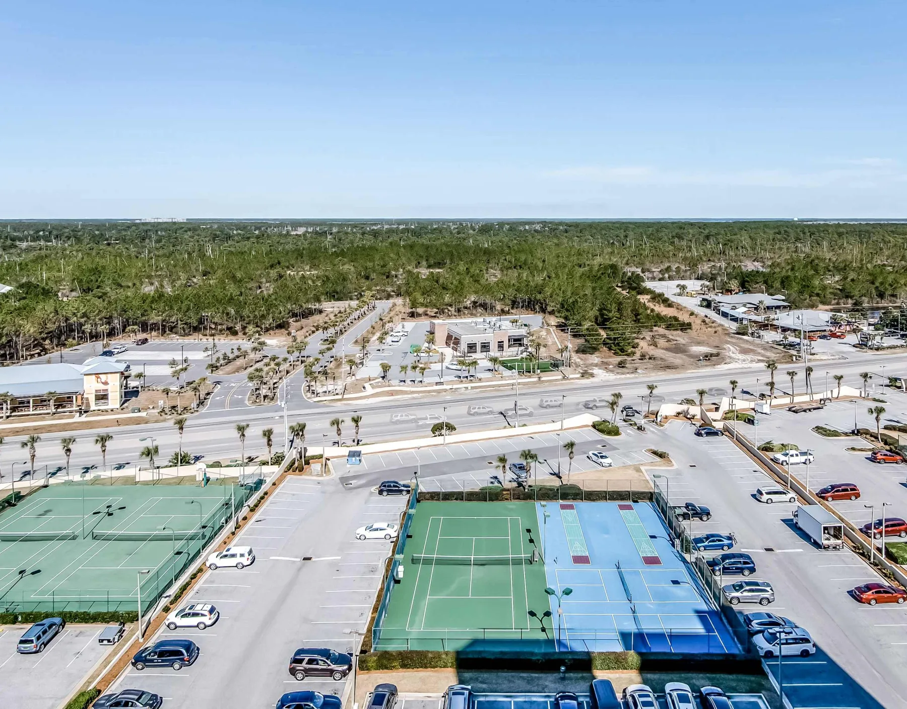 Zona común: Vista aérea de canchas de tenis al aire libre junto a un estacionamiento.