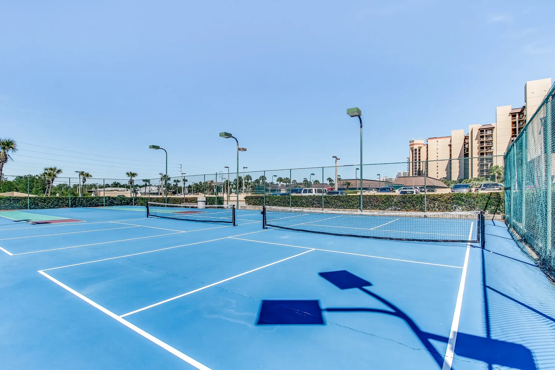 Zona común: Canchas de tenis al aire libre con superficies azules y redes bajo un cielo despejado.