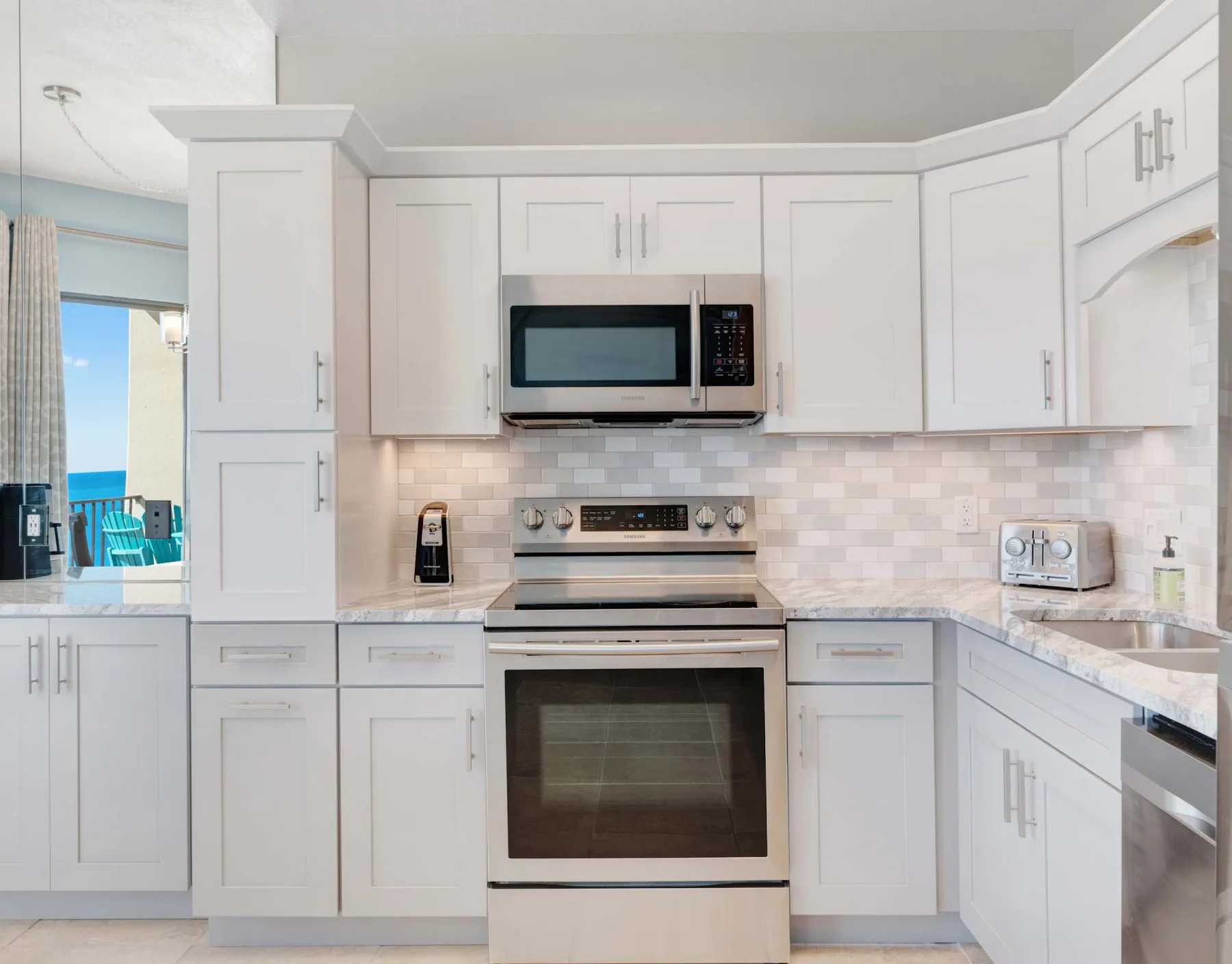 Una cocina luminosa con gabinetes blancos, un microondas y un horno empotrado.