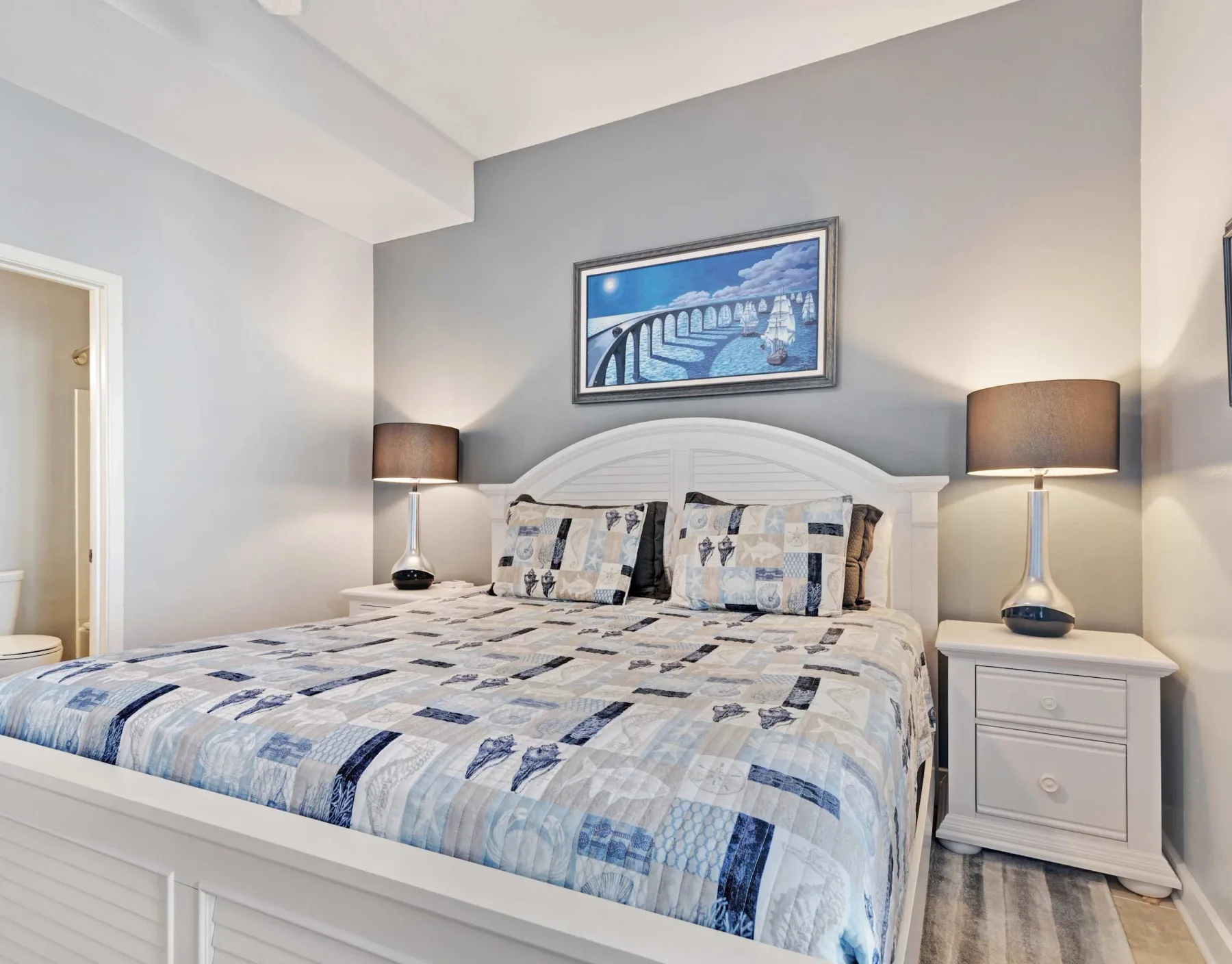 Dormitorio con una cama grande vestida con ropa de cama estampada en azul y blanco.