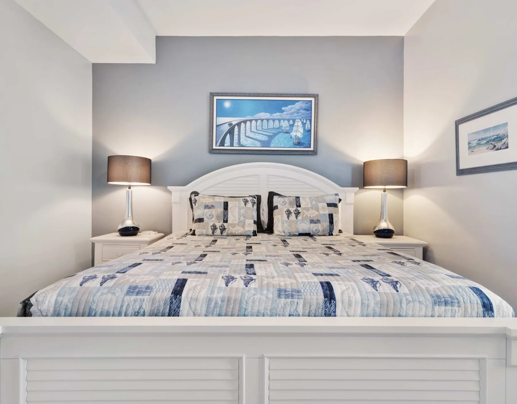 Un dormitorio con una cama bien tendida y lámparas a ambos lados.