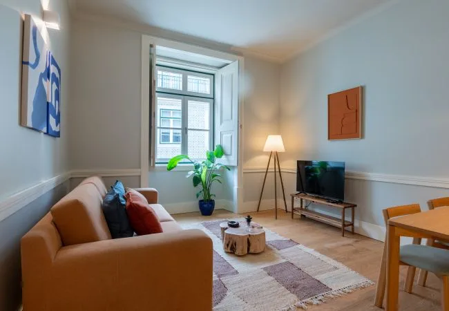 A living room with seating, a television, and a large window.