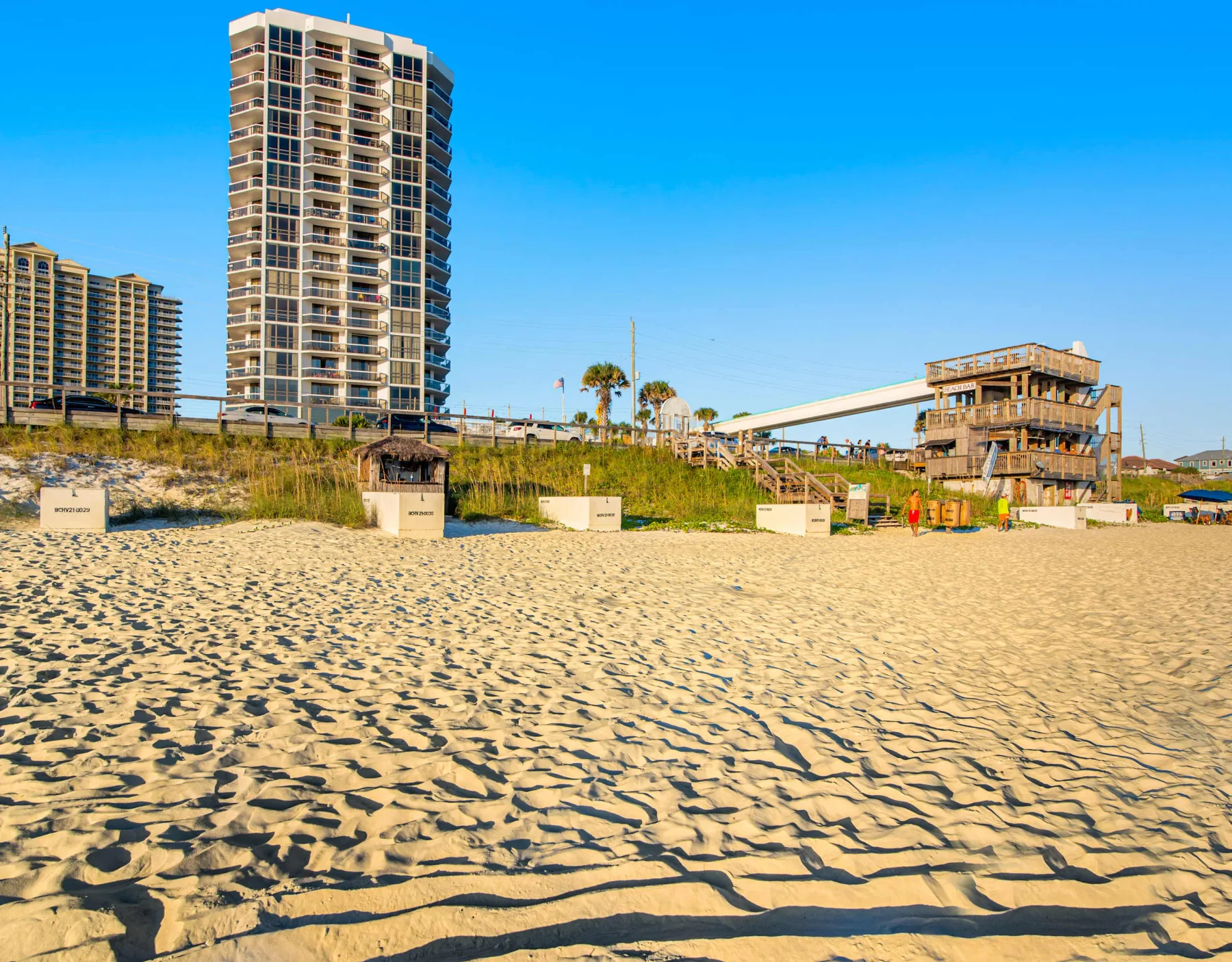 Shared amenity: A sandy beach with high-rise buildings and a low structure in the background.